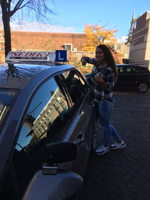 Leerling van Autorijschool Sediki naast de lesauto in Gouda