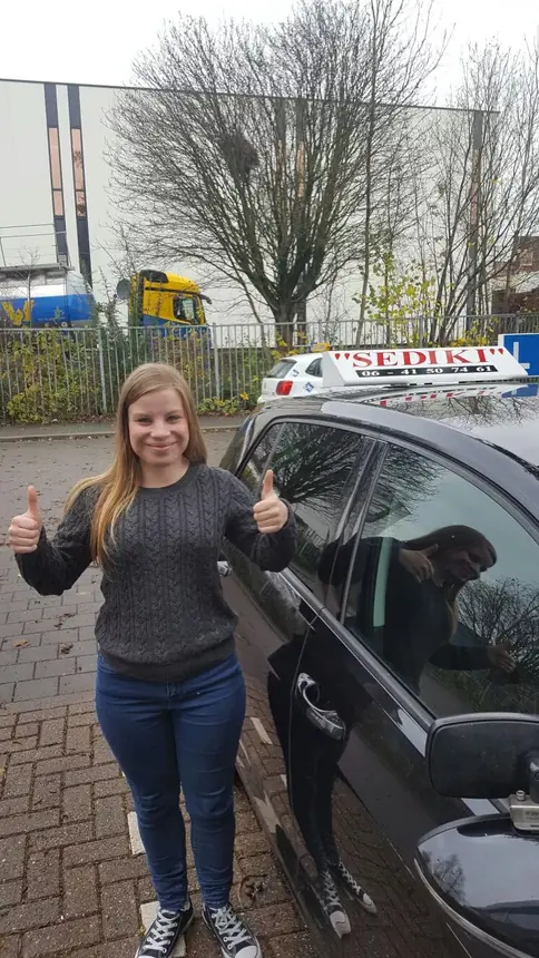 Leerling van Autorijschool Sediki viert haar rijbewijs naast de lesauto