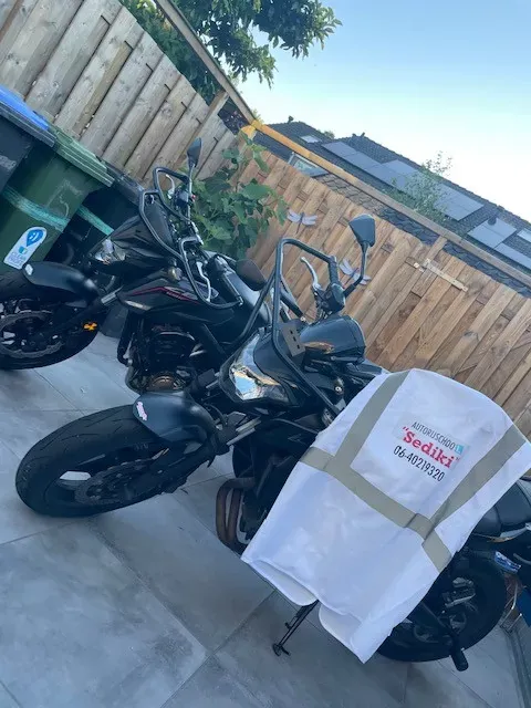 De twee lesmotoren van Motorrijschool Sediki met het motorhesje van de rijschool